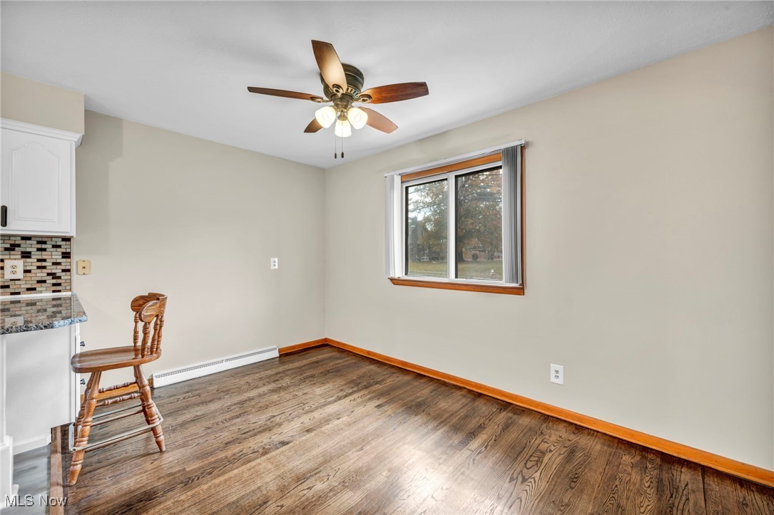 10927 Granger Road Cleveland, OH 44125 - Photo 13 of 33 Unfurnished dining area with dark wood-type flooring, a baseboard heating unit, and ceiling fan