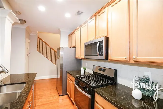 a kitchen with stainless steel appliances granite countertop a stove a sink and a microwave