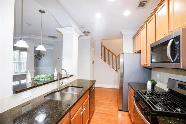 a kitchen with stainless steel appliances granite countertop a sink a stove and a wooden floors