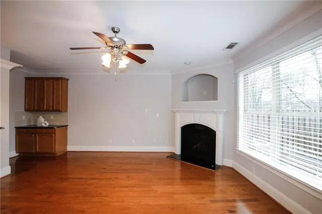 a view of a livingroom with a fireplace a ceiling fan and windows