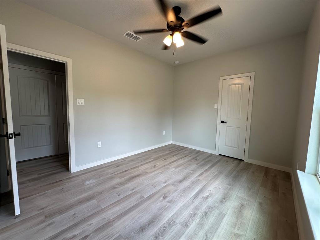 317 North Clark Street Comanche, TX 76442 - Photo 15 of 35 an empty room with wooden floor and a ceiling fan
