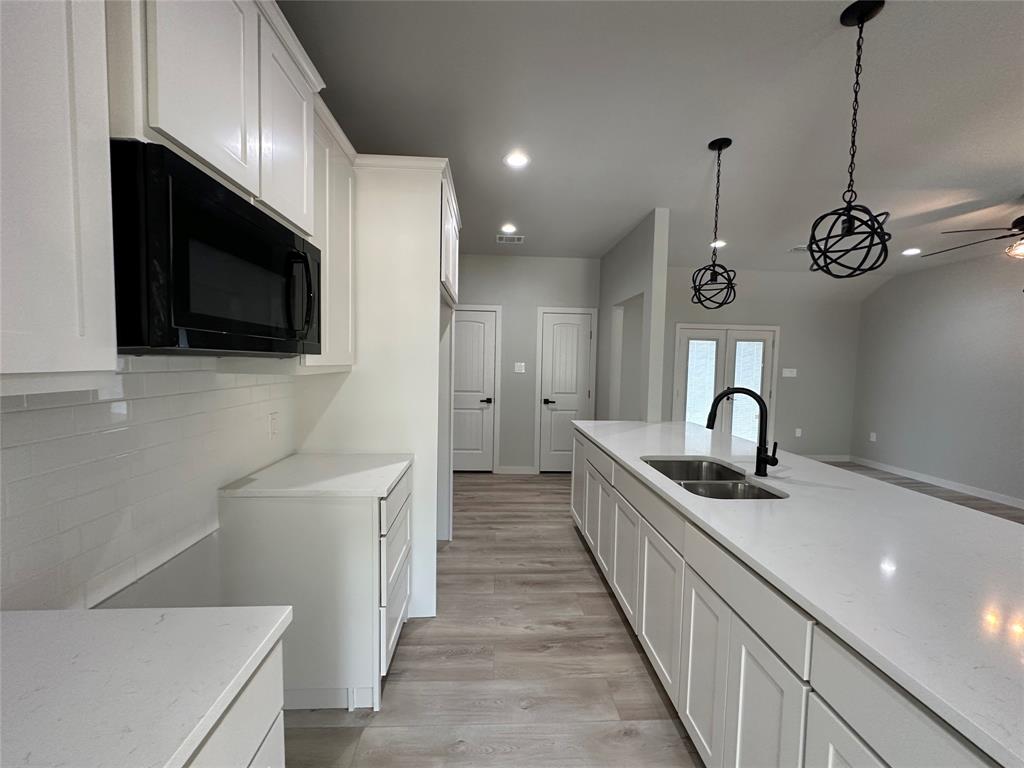 317 North Clark Street Comanche, TX 76442 - Photo 9 of 35 a kitchen with stainless steel appliances granite countertop a sink and a stove top oven with wooden floor