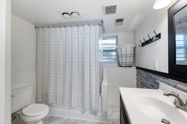 a bathroom with a sink a toilet a mirror and shower