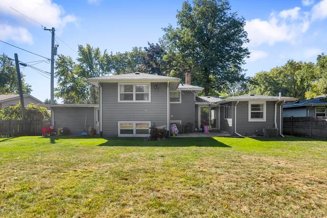 a view of a house with a yard and a large tree