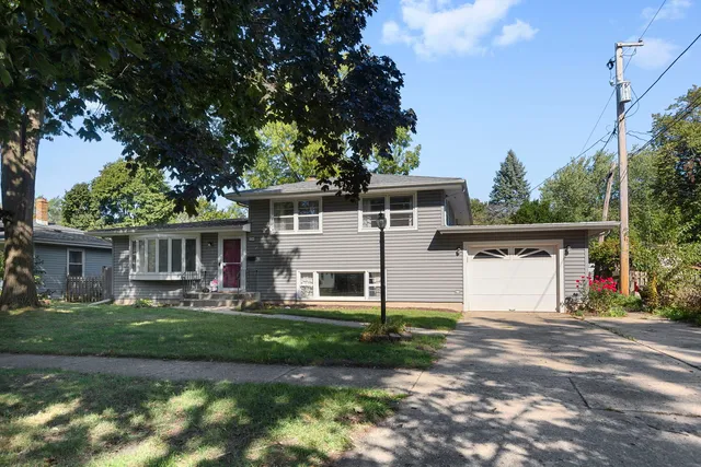a front view of a house with a garden and trees