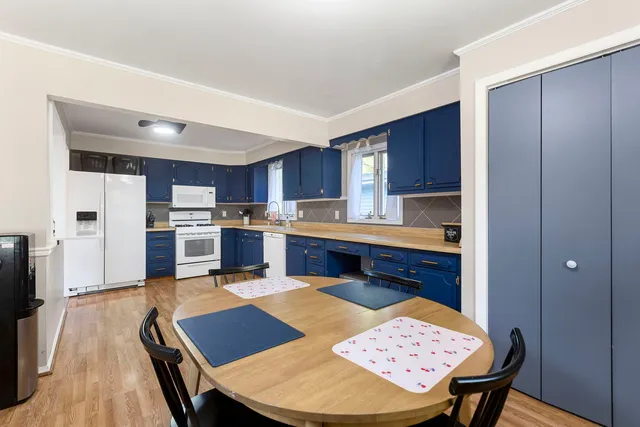a kitchen with stainless steel appliances kitchen island granite countertop wooden cabinets a dining table and chairs