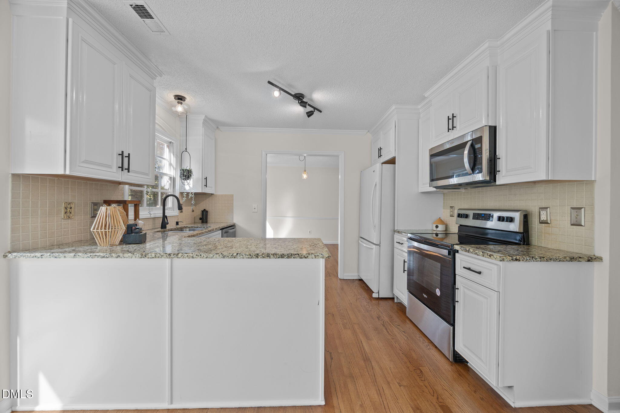 102 Korbel Place Cary, NC 27513 - Photo 14 of 43 a kitchen with stainless steel appliances granite countertop a stove top oven a sink a refrigerator with white cabinets and wooden floor