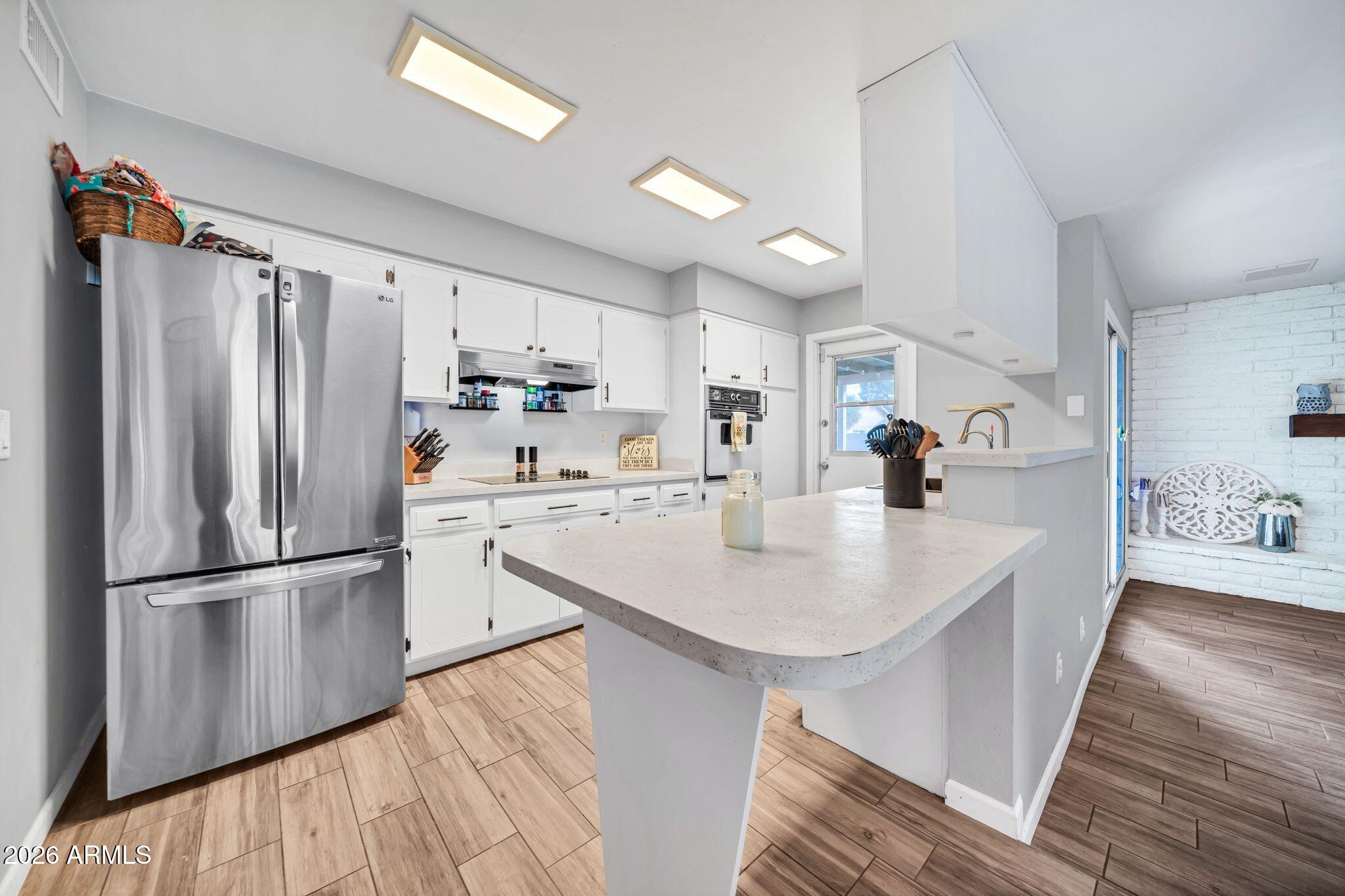 3041 West Acoma Drive Phoenix, AZ 85053 - Photo 3 of 35 a kitchen with stainless steel appliances granite countertop a refrigerator a sink dishwasher a stove and white countertops with wooden floor