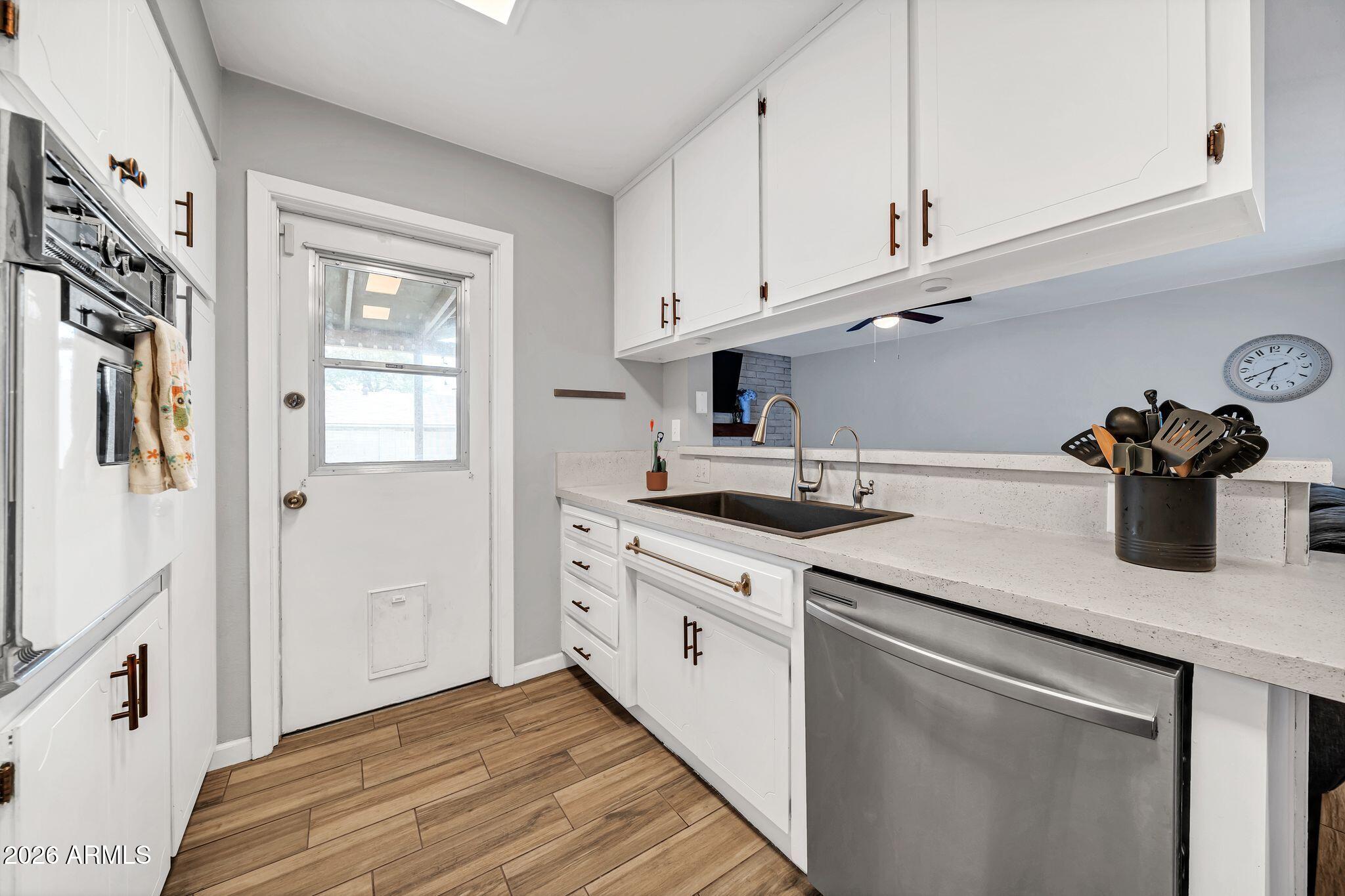 3041 West Acoma Drive Phoenix, AZ 85053 - Photo 31 of 35 a kitchen with stainless steel appliances granite countertop a sink dishwasher and white cabinets with wooden floor