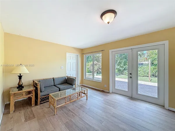 an empty room with wooden floor chandelier fan and windows