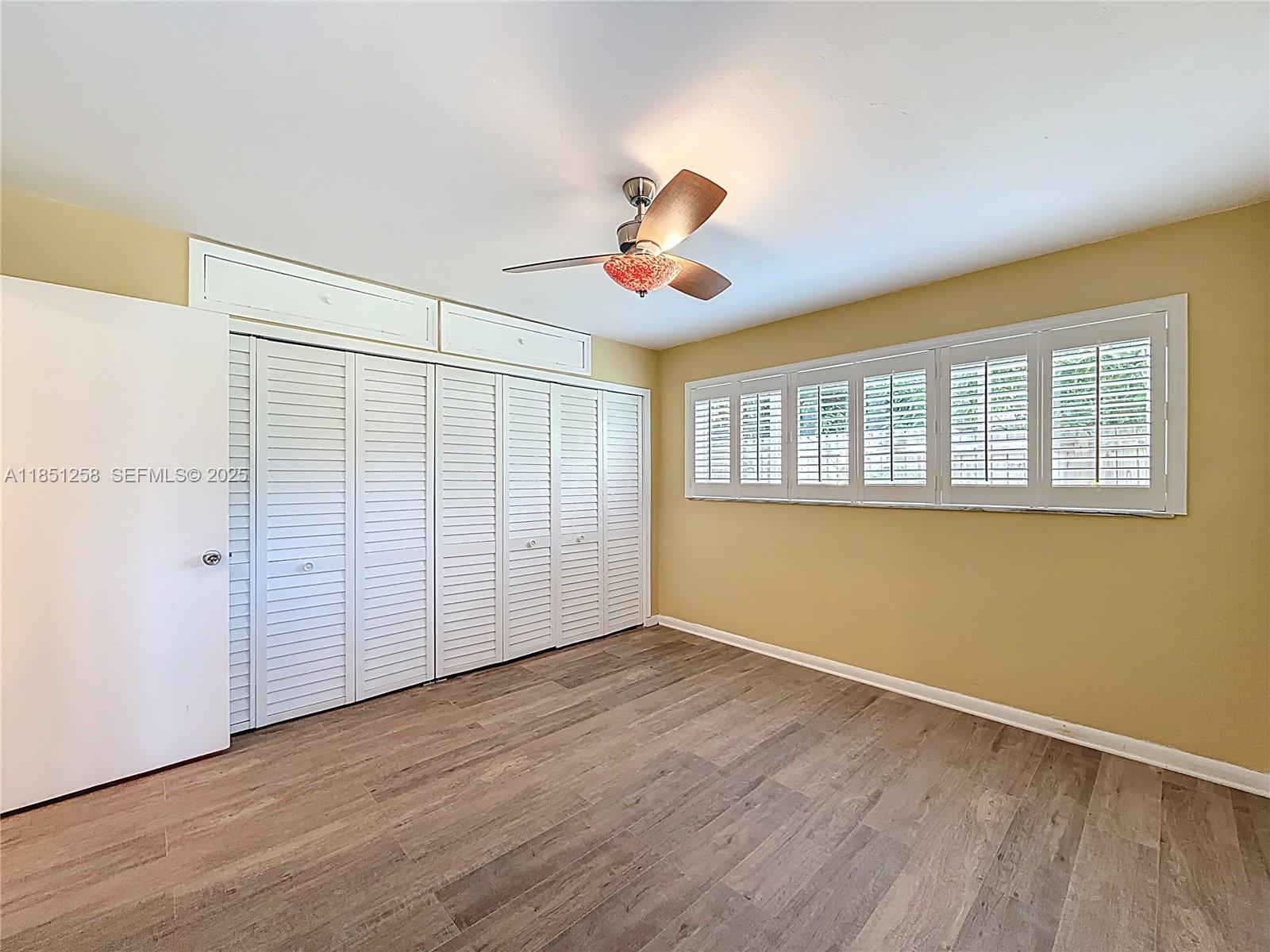 4911 Northeast 24th Avenue Lighthouse Point, FL 33064 - Photo 29 of 63 an empty room with wooden floor chandelier fan and windows