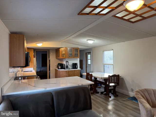 a large kitchen with stainless steel appliances kitchen island granite countertop a stove a sink dishwasher and a microwave with wooden floor