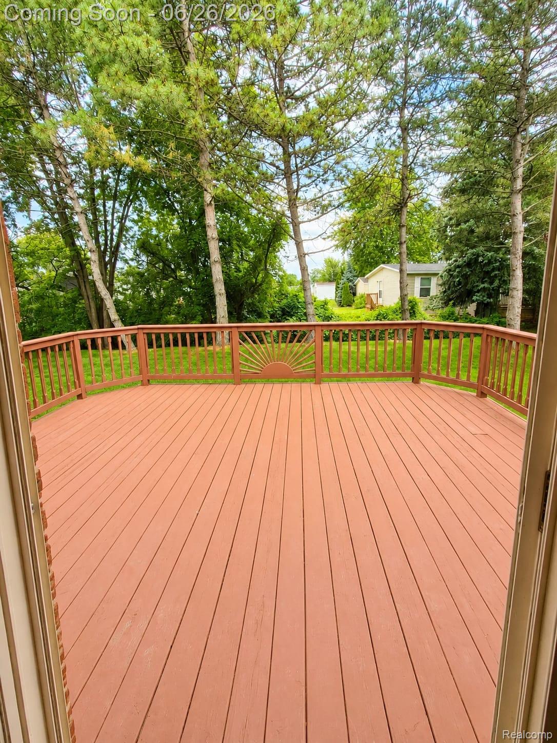 17014 Country Ridge Lane Macomb, MI 48044 - Photo 24 of 25 Spacious outdoor deck featuring red-toned wood flooring and a curved railing with decorative sunburst detail