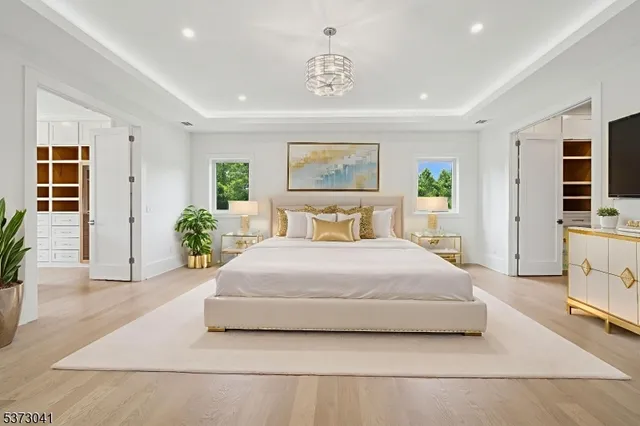 a large white kitchen with stainless steel appliances kitchen island granite countertop a lot of cabinets and a wooden floor