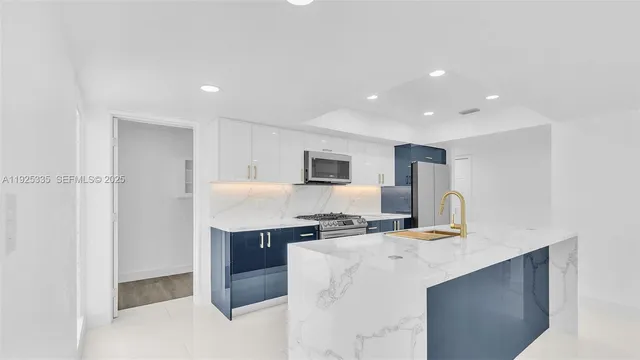 a kitchen with kitchen island stainless steel appliances a sink and a refrigerator