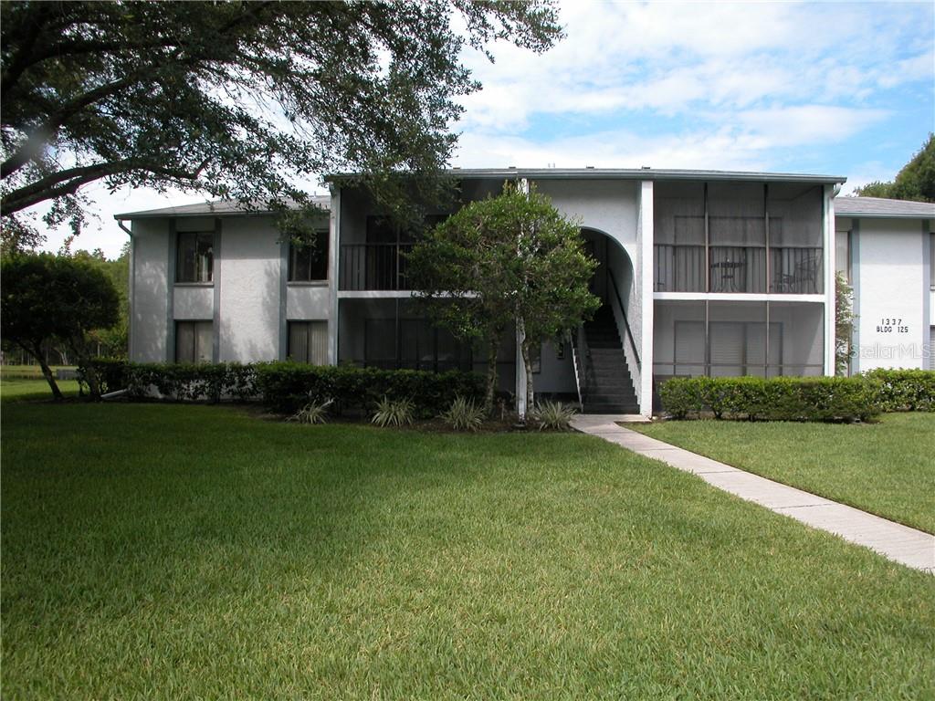 1337 Pine Ridge Circle East, Unit A2 Tarpon Springs, FL 34688 - Photo 1 of 1 a front view of a house with a yard and trees
