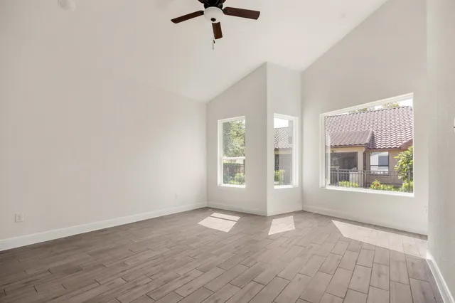 a view of an empty room with a window and wooden floor