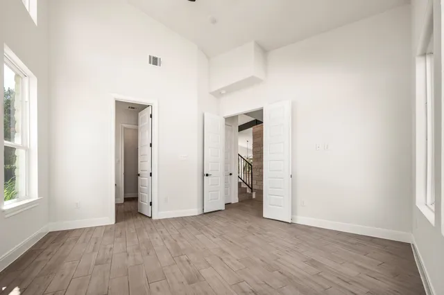 an empty room with wooden floor and windows