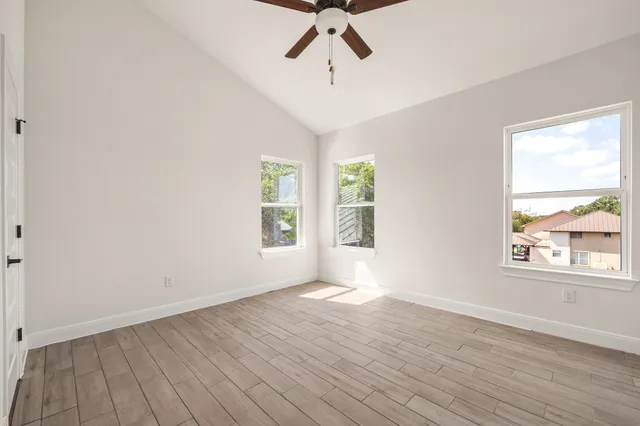 a view of empty room with wooden floor and fan