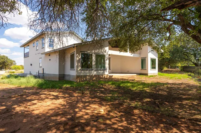 a backyard of a house with plants and large tree