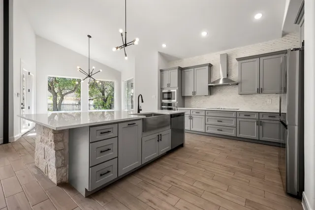 a kitchen with stainless steel appliances kitchen island granite countertop a stove a sink and a refrigerator