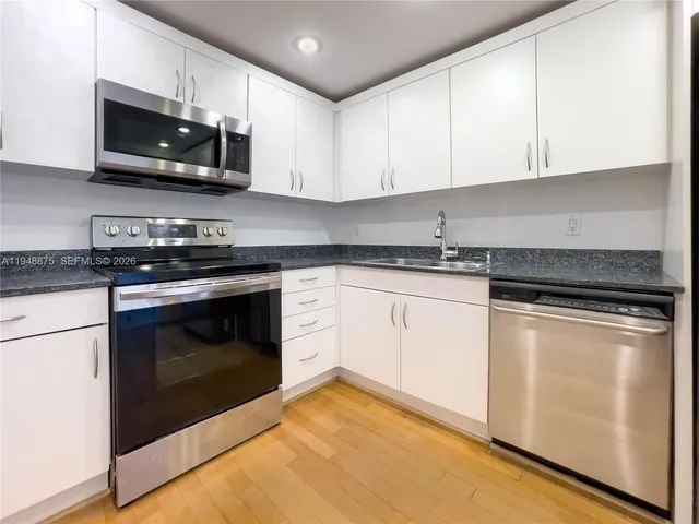 a kitchen with stainless steel appliances granite countertop white cabinets sink and stove