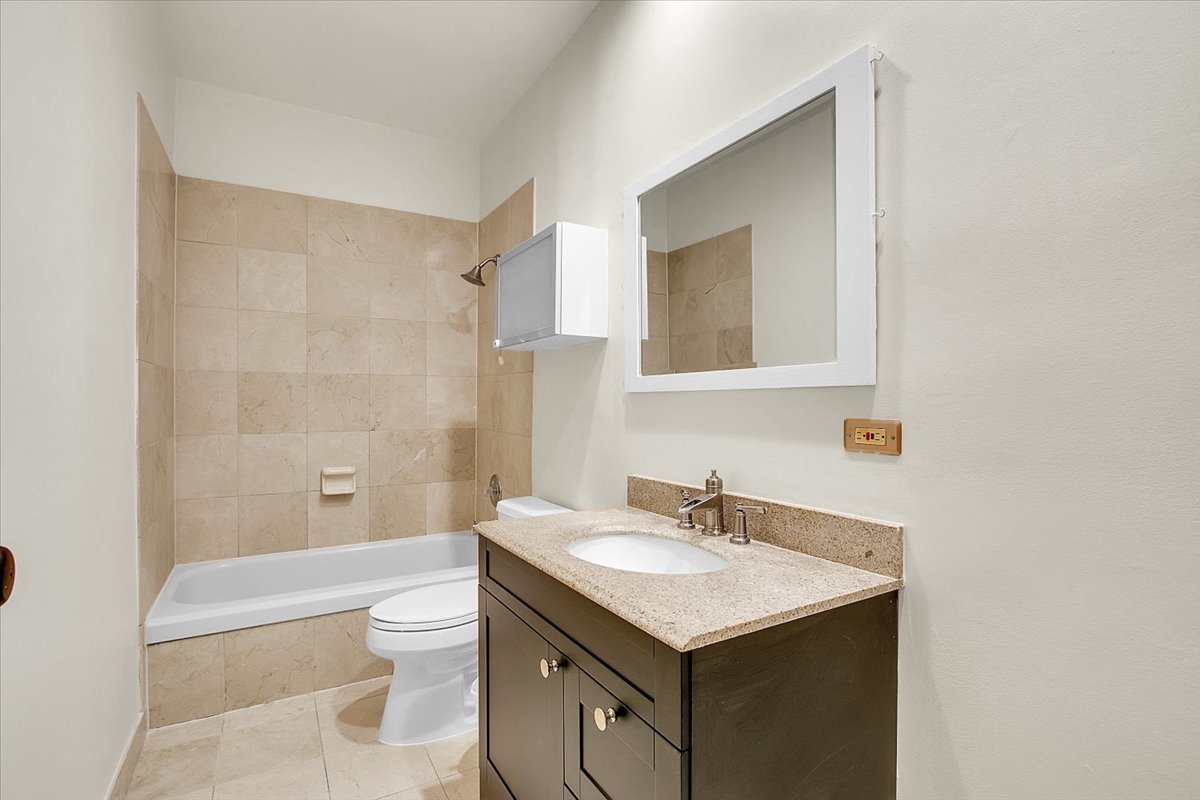 550 West Surf Street, Unit 115 Chicago, IL 60657 - Photo 13 of 18 a bathroom with a granite countertop sink toilet and shower