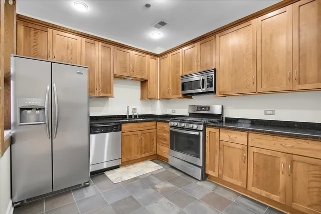a kitchen with stainless steel appliances granite countertop a refrigerator a stove and a sink