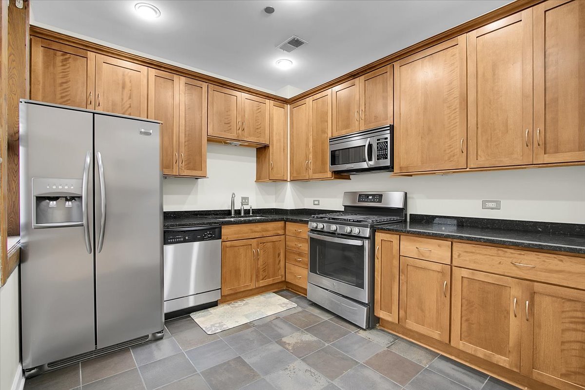 550 West Surf Street, Unit 115 Chicago, IL 60657 - Photo 8 of 18 a kitchen with stainless steel appliances granite countertop a refrigerator stove microwave and sink