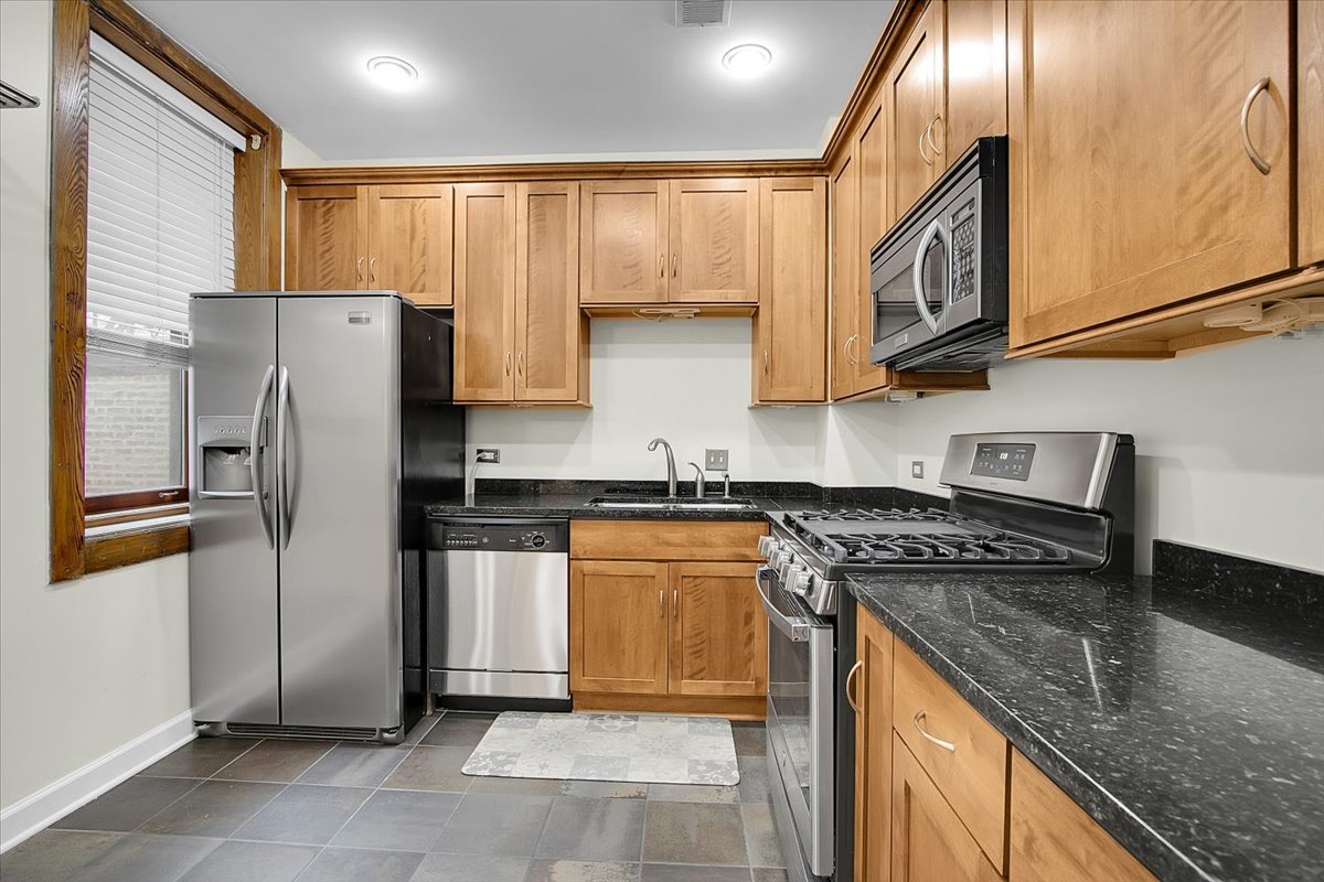 550 West Surf Street, Unit 115 Chicago, IL 60657 - Photo 9 of 18 a kitchen with stainless steel appliances granite countertop a refrigerator a stove and a sink