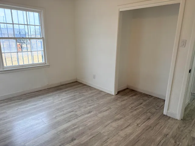an empty room with wooden floor and windows