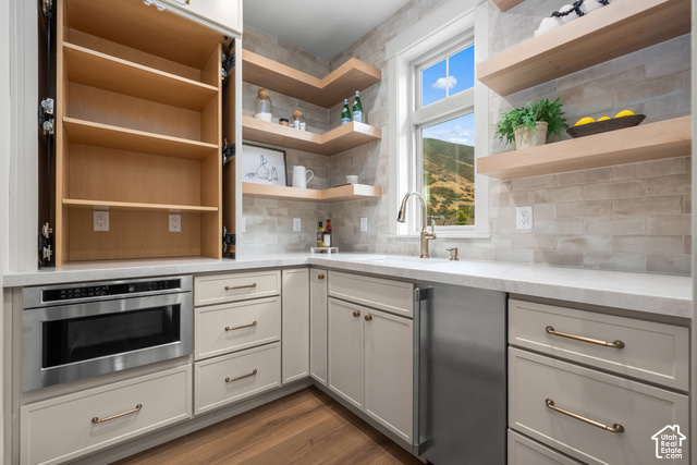 1175 North Elk Rdg Lane, Unit 201 Alpine, UT 84004 - Photo 20 of 38 Built-in stainless steel microwave, light-toned custom cabinetry, polished countertop, undermount sink with a gooseneck faucet, and light wood-finish floating shelves