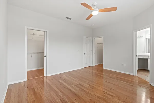 a view of empty room with wooden floor and ceiling fan