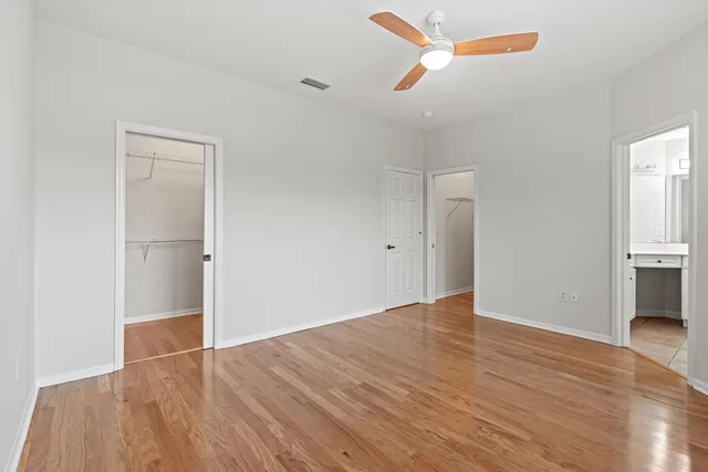 a view of empty room with wooden floor and ceiling fan