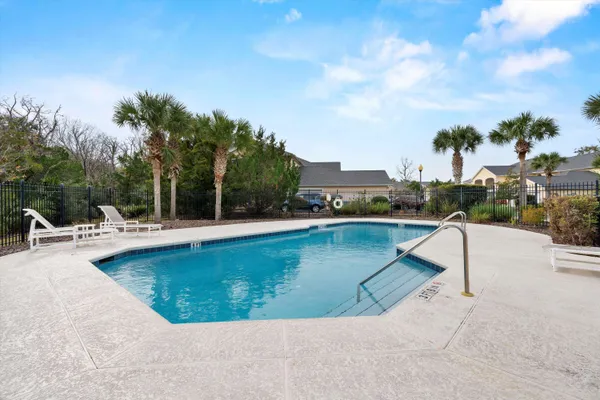a view of a swimming pool with lounge chair and palm trees