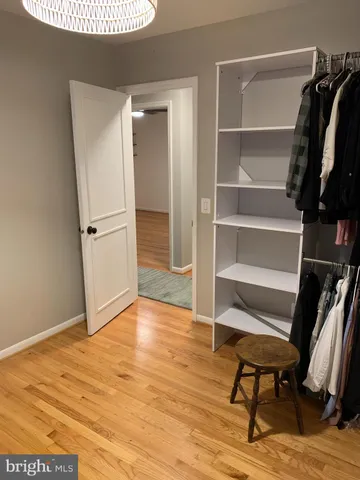 a view of a hallway with wooden floor and a bathroom