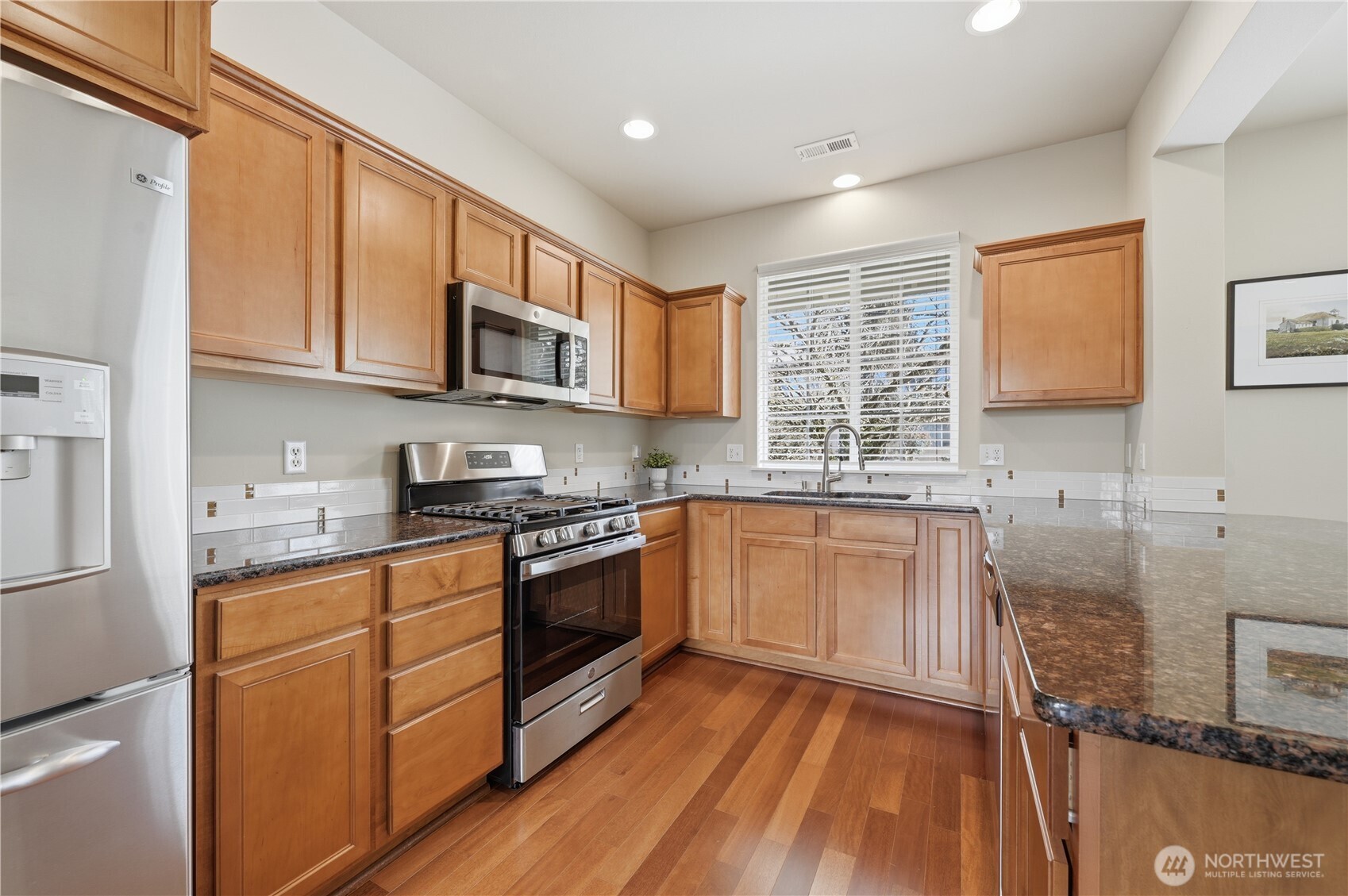 18635 101st Avenue Northeast, Unit 6 Bothell, WA 98011 - Photo 5 of 23 a kitchen with stainless steel appliances granite countertop wooden cabinets a stove a sink and a microwave