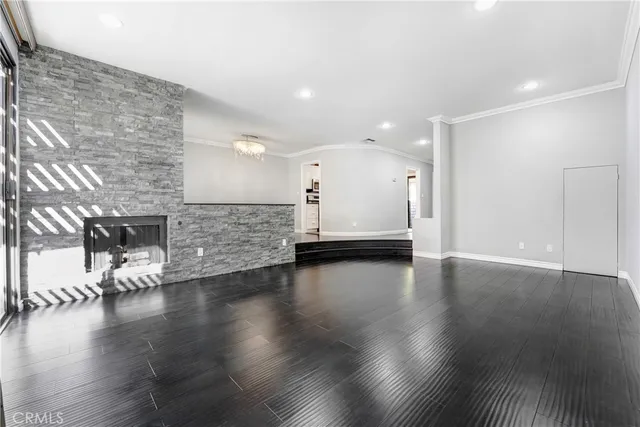 an empty room with wooden floor and a kitchen