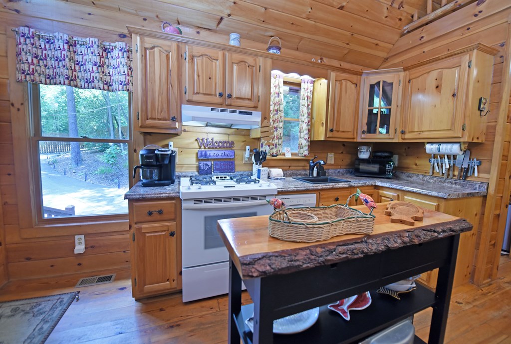 789 Old Mill Pond Road Mineral Bluff, GA 30559 - Photo 31 of 59 a kitchen with granite countertop a stove a sink and a wooden cabinets
