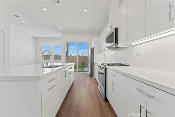 a kitchen with stainless steel appliances sink stove refrigerator and cabinets