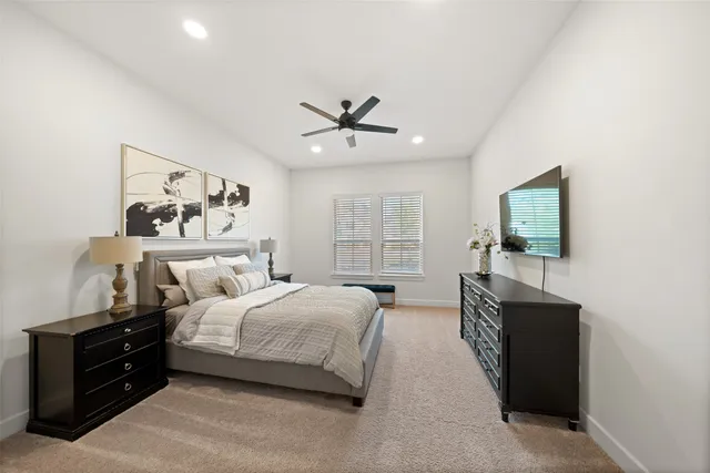 a spacious bedroom with a bed a couch and a ceiling fan