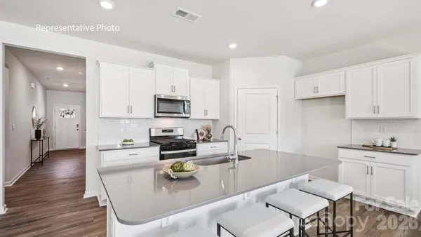 a kitchen with stainless steel appliances granite countertop a sink dishwasher a stove a refrigerator a microwave oven with white cabinets and wooden floor