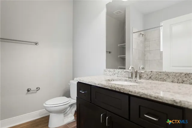 a bathroom with a granite countertop sink a toilet and a mirror