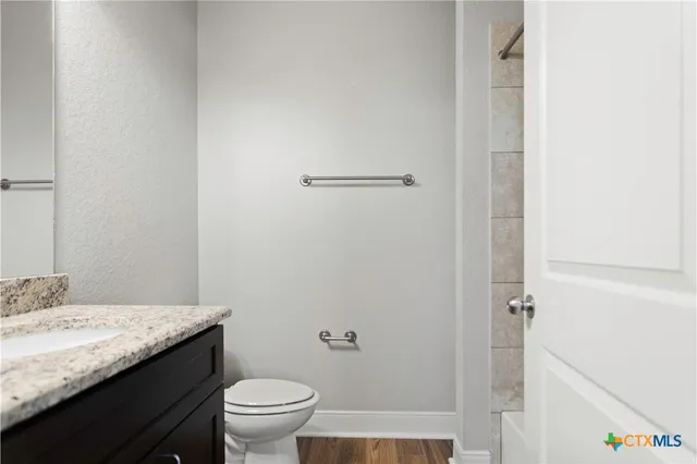 a bathroom with a granite countertop sink toilet and a mirror