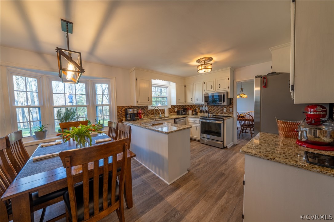 6720 Greenyard Road Chester, VA 23831 - Photo 31 of 46 a kitchen with stainless steel appliances granite countertop a refrigerator a stove top oven a dining table and chairs with wooden floor