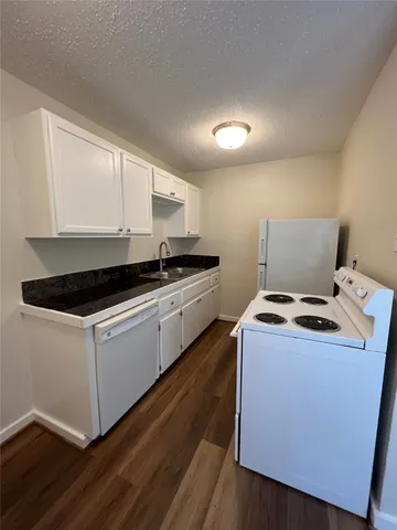 a kitchen with sink a stove and white cabinets