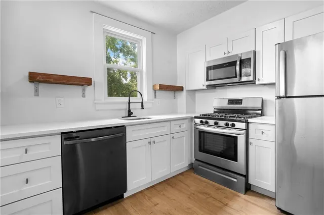 a kitchen with stainless steel appliances white cabinets a sink and a stove