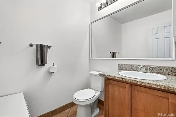 a bathroom with a granite countertop toilet sink and mirror