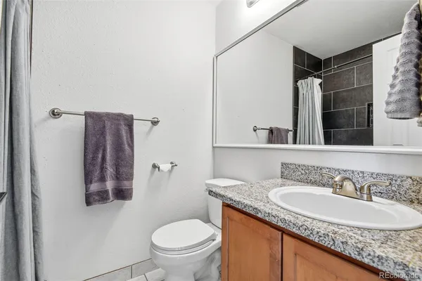 a bathroom with a granite countertop sink toilet and shower
