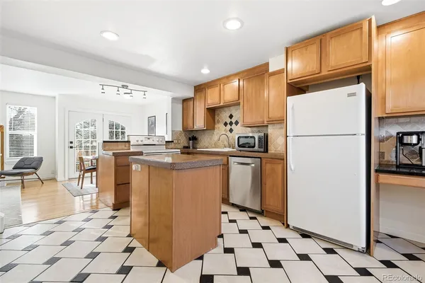 a kitchen with granite countertop a refrigerator a stove a sink a dining table and chairs